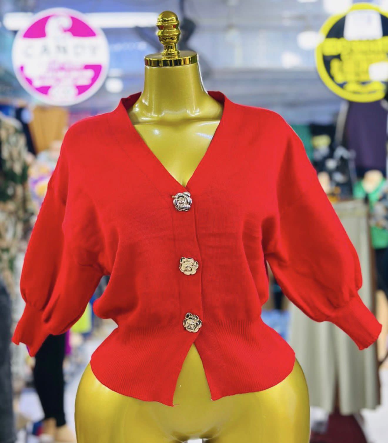 A knitted cardigan or sweater top characterised by its prominent silver/gold-tone heart-shaped buttons and has a slightly cropped length with long, voluminous balloon sleeves that end in ribbed cuffs.