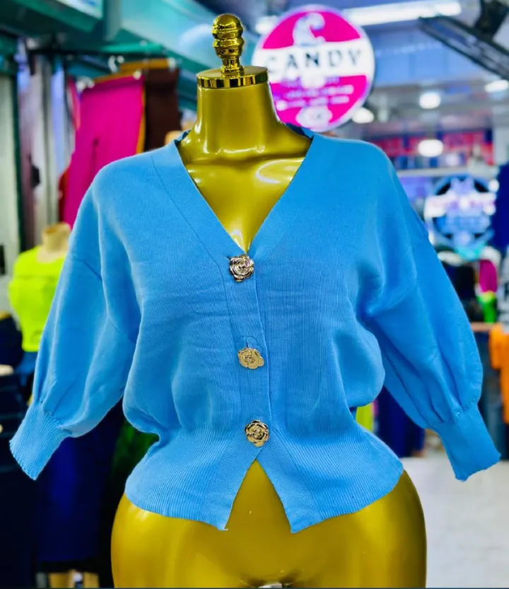 A knitted cardigan or sweater top characterised by its prominent silver/gold-tone heart-shaped buttons and has a slightly cropped length with long, voluminous balloon sleeves that end in ribbed cuffs.