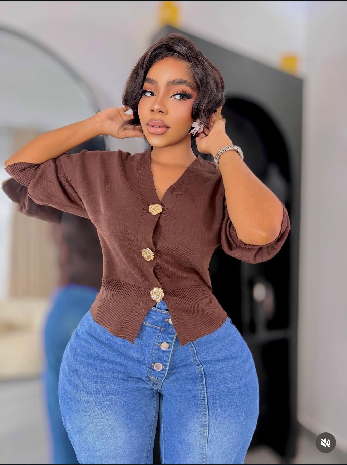 A knitted cardigan or sweater top characterised by its prominent silver/gold-tone heart-shaped buttons and has a slightly cropped length with long, voluminous balloon sleeves that end in ribbed cuffs.
