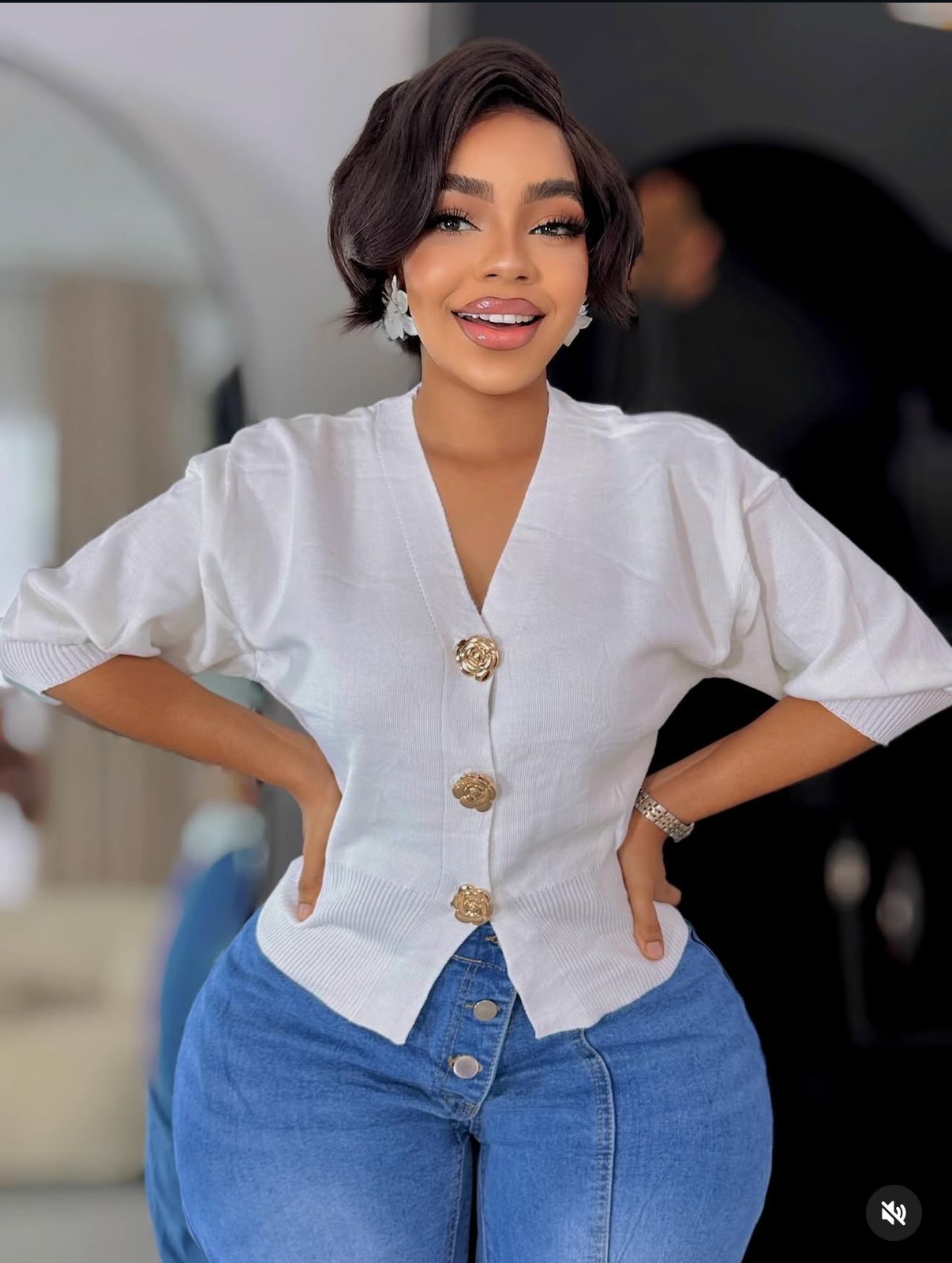 A knitted cardigan or sweater top characterised by its prominent silver/gold-tone heart-shaped buttons and has a slightly cropped length with long, voluminous balloon sleeves that end in ribbed cuffs.
