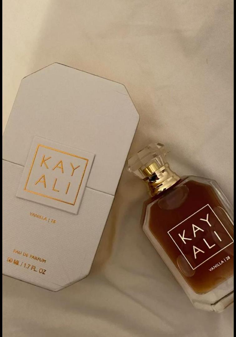 100Ml Kayali Vanilla | 28 perfume in a faceted glass bottle with gold accents and a crystal-like cap. Deep amber-red juice inside. The label shows "KAY ALI" in gold within a square frame.