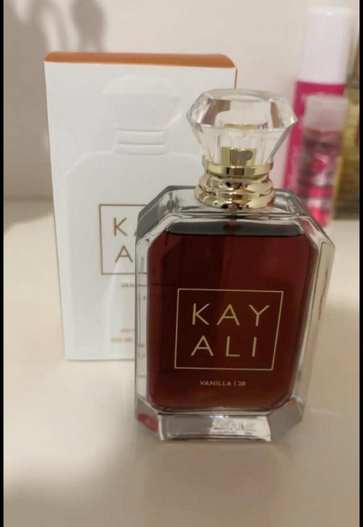 100Ml Kayali Vanilla | 28 perfume in a faceted glass bottle with gold accents and a crystal-like cap. Deep amber-red juice inside. The label shows "KAY ALI" in gold within a square frame.